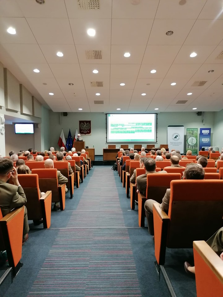 Zdjęcie przedstawia widok od tyłu wypełnionej gośćmi sali konferencyjnej z odbywającą się na podium prezentacją. Fot. T. Maćkowiak (RDLP w Poznaniu).